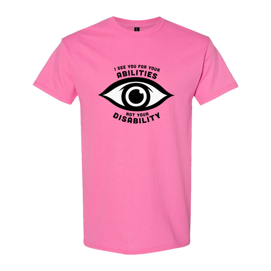 Pink t-shirt featuring an eye graphic and the text “I see you for your abilities, not your disability.”
